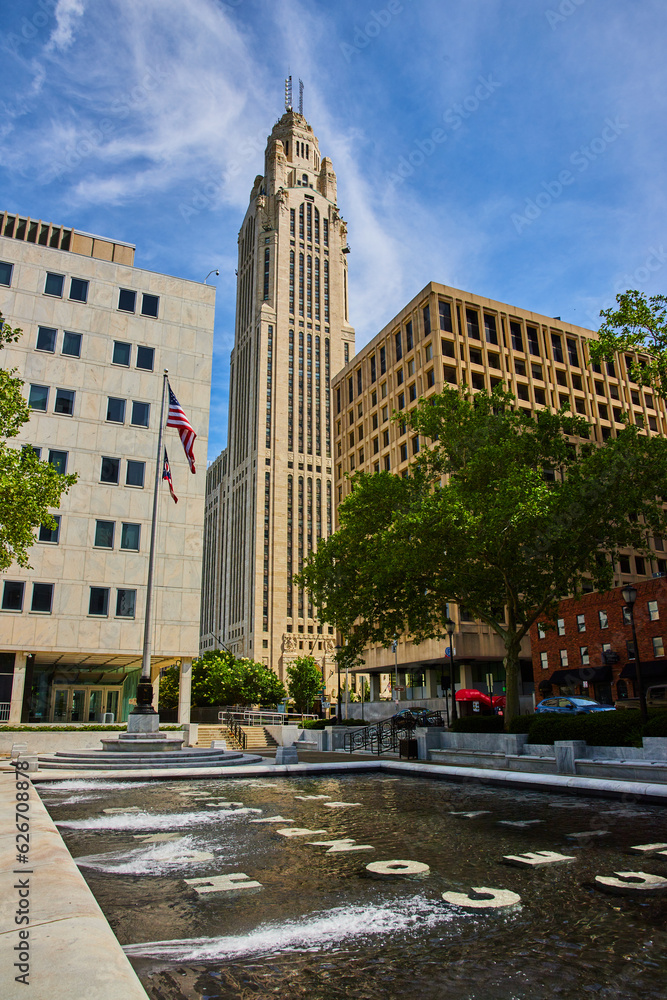 Stone words at bottom of fountain with American and Ohio flags and LeVeque Tower in background