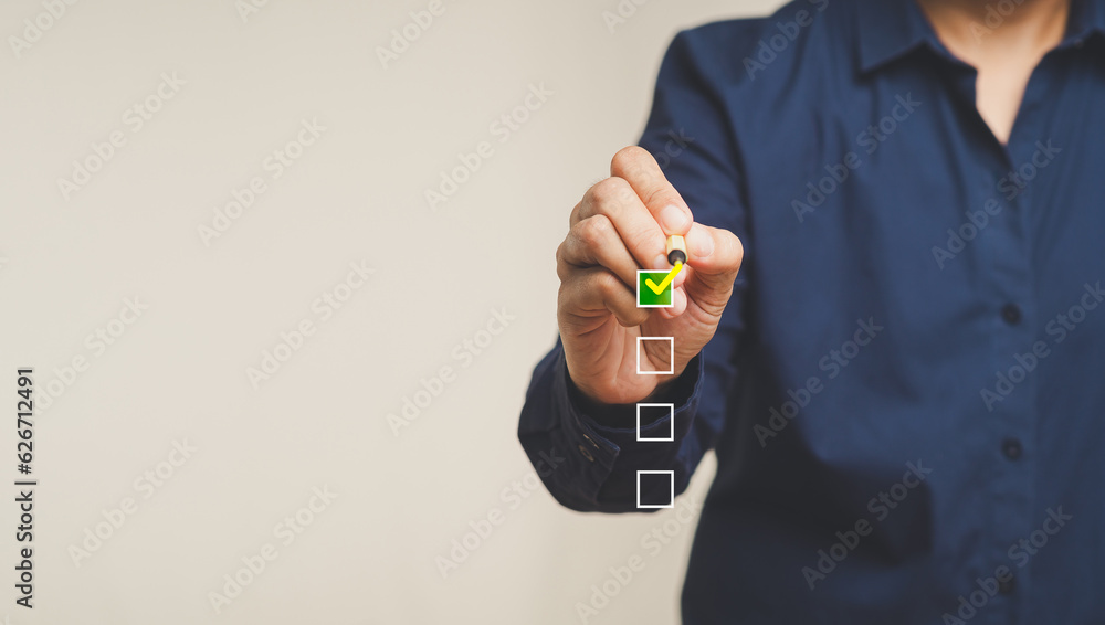 Fototapeta premium Businessman ticks the correct sign with yellow marks in checkboxes while standing on a gray background.