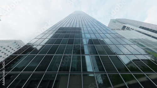 The camera spins around a skyscraper with mirrored windows in the heart of the business district. Seamless loop.