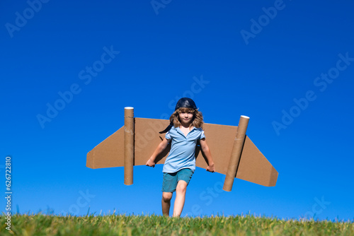 Boy child with wings at sky imagines a pilot and dreams of flying. Kids adventure, children freedom and imagination concept.