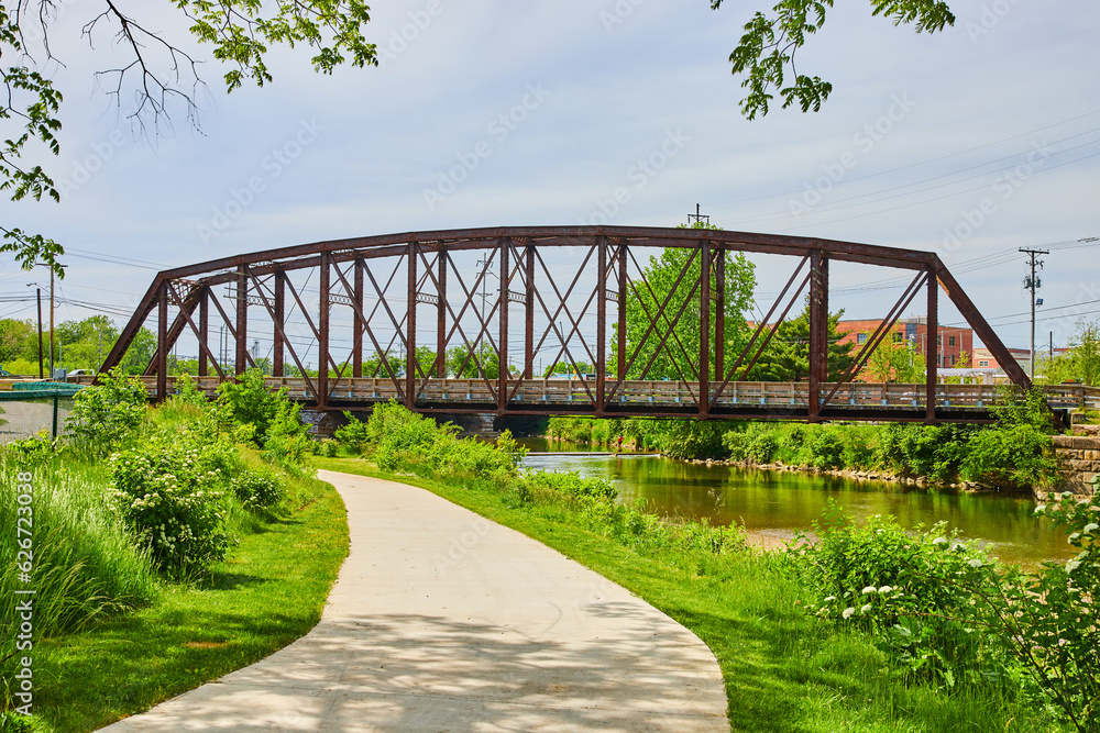 Fototapeta premium Old train bridge over Kokosing River with sidewalk path leading to it