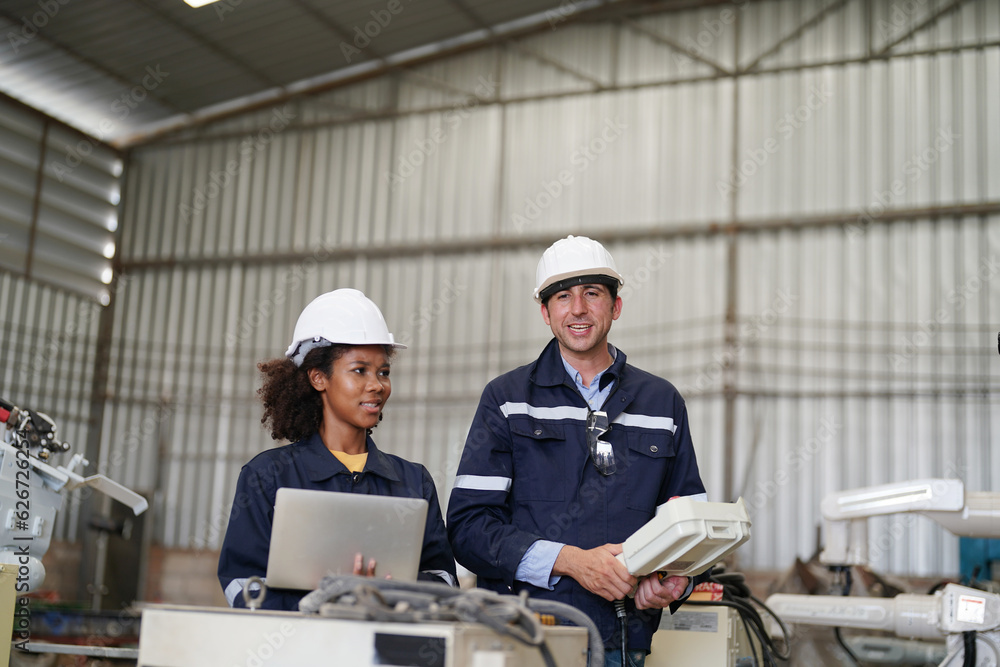 Multiracial industrial engineers working at automated AI robotic production factory, New industrial technology concept.