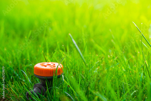 Orange sprayer with different modes of watering the lawn, close-up on a blurred background. Multifunctional sprinkler with adjustable modes of direction and intensity of watering