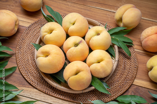 Yellow Peach on wooden basket, Peach with leaf on wooden background.