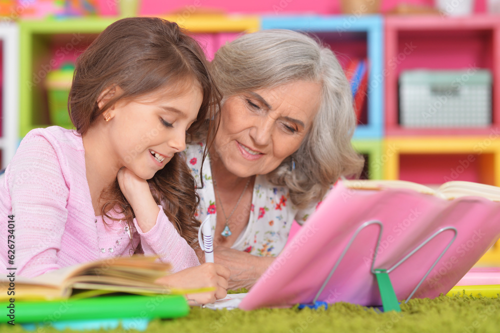 portrait of granddaughter with grandmother doing homework and reading books portrait of granddaughter with grandmother doing homework and reading books