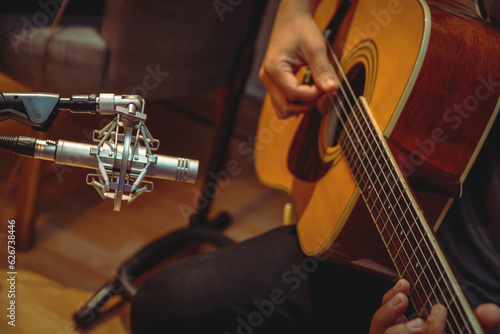 Hombre tocando la guitarra acústica clásica listo para grabar con su micrófono de condensador