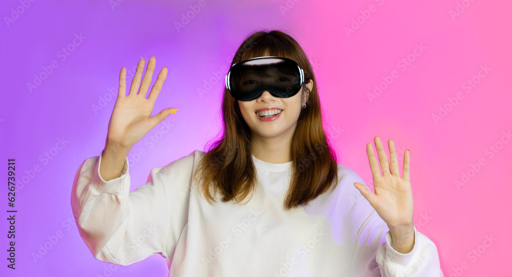 Asian woman wearing AR glasses vision pro and pointing finger isolated on pink and purple neon background Asian woman wearing AR glasses vision pro and pointing finger isolated on pink and purple neon background