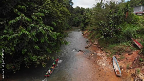 kampung sampan moving through a rural river beside a longhouse photo