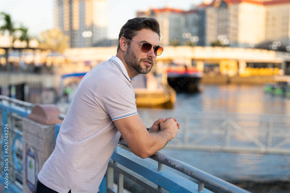 Stylish man wearing sunglasses and shirt. Handsome man outdoors portrait. Portrait of stylish male model outdoor. Fashion male posing near skyscraper on the street. Fashionable man in urban style. Stylish man wearing sunglasses and shirt. Handsome man outdoors portrait. Portrait of stylish male model outdoor. Fashion male posing near skyscraper on the street. Fashionable man in urban style.