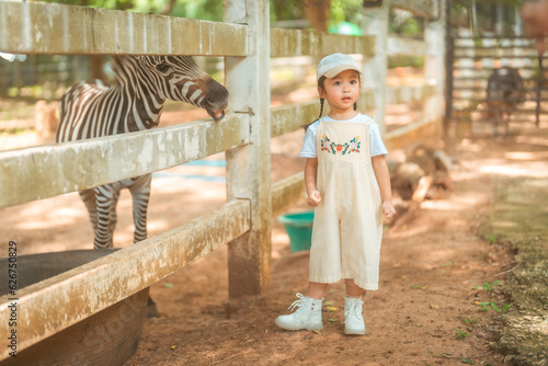 cute baby girl in dress and hat with activity feed food zebra with happy time on outdoor