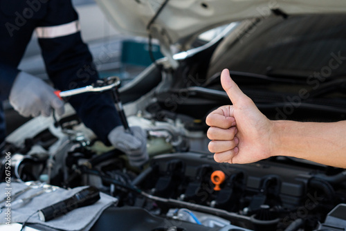 Hand of customer thumbs up for good service in auto repair shop.Customer review.Repair service.Car Machanic.Car repair and maintenanc concept. © witsarut