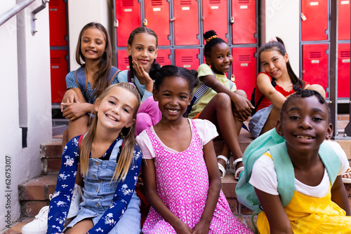 Fototapeta Portrait of diverse happy schoolgirls in elementary school cloakroom