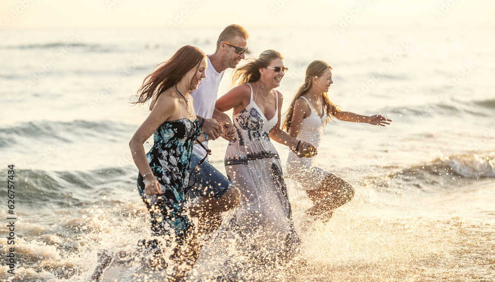 The complete family runs hand in hand from the beach to the sea, enjoying a joint vacation by the sea. The complete family runs hand in hand from the beach to the sea, enjoying a joint vacation by the sea.