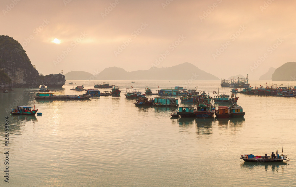 Colorful fishing boats on a sea near to rock islands on sunset. Ha Long Bay, Vietnam.