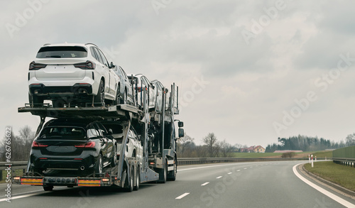 Photography Car transporter carries new luxury vehicles along the motorway, back view of the trailer