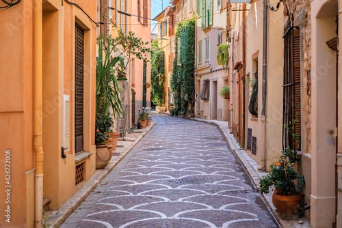 Fototapeta Naklejka Na Ścianę i Meble -  Ornate mosaic street pavement between traditional old houses near the covered provencal farmers market in old town or Vieil Antibes, South of France