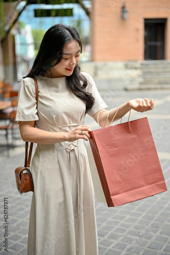 A happy Asian woman walking with her shopping bags, enjoying her weekend at the outlet centre