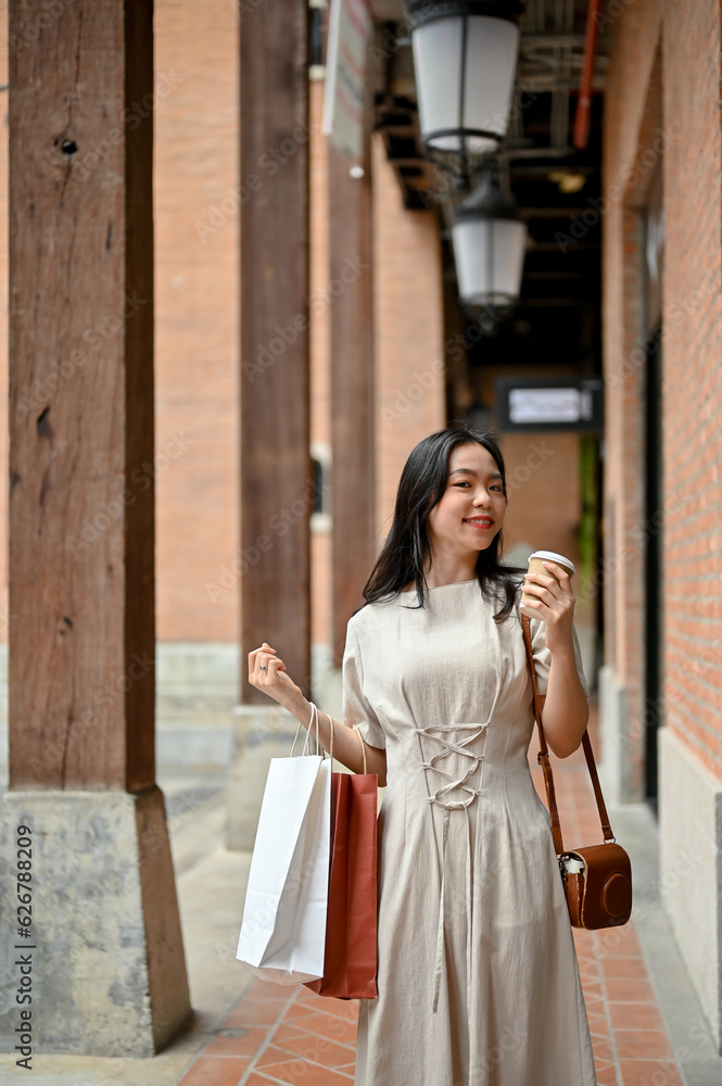 A beautiful Asian woman carrying her shopping bags while strolling around the city