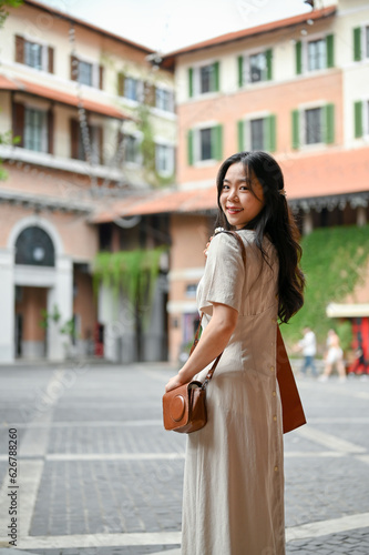 A charming Asian woman in a pretty dress strolling in the beautiful city alone on her vacation.