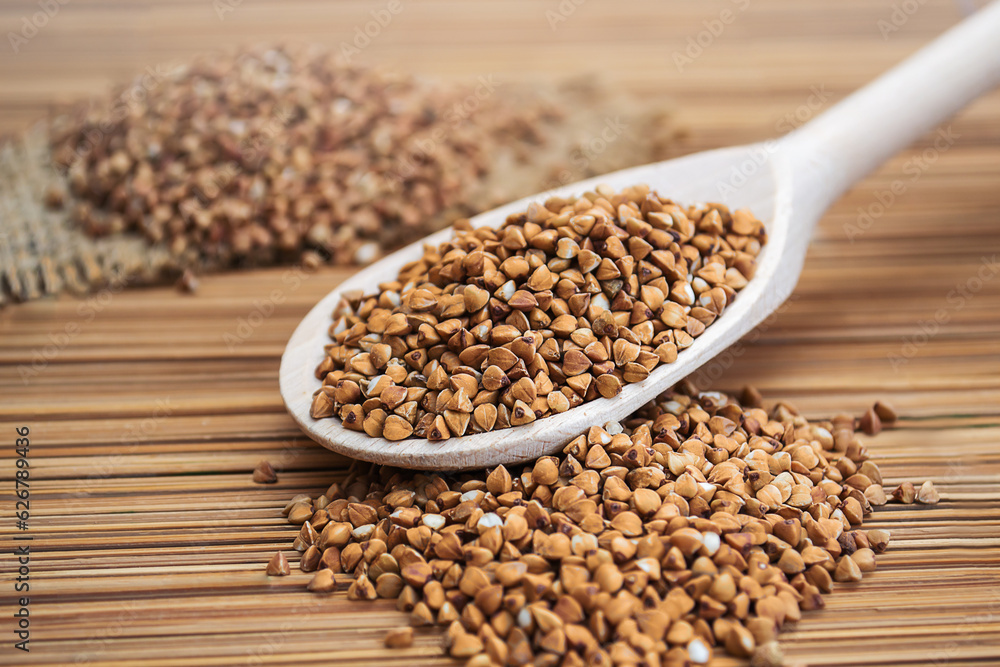 A wooden spoon filled with buckwheat on top of a bamboo mat A wooden spoon filled with buckwheat on top of a bamboo mat