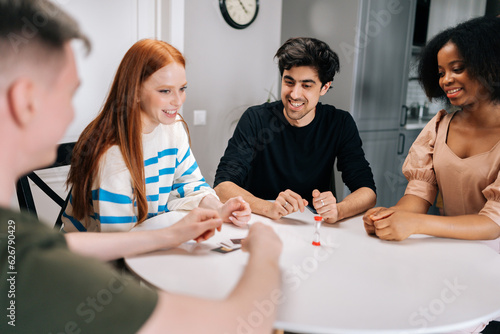 Canvas Print Cheerful multiethnic friends having fun with charades cards play, enjoying board games activity for entertainment at home