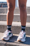 cropped vertical photo with close up of strong legs of a female runner outdoors, concept of sport and active lifestyle