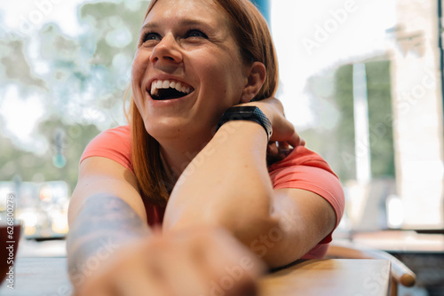 Cheerful redhead woman leaning on table in cafe photo