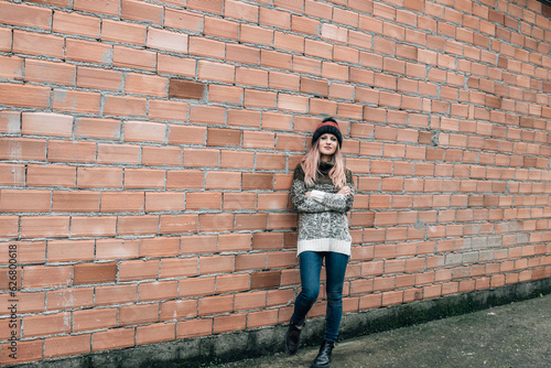 young woman in winter clothes on brick wall