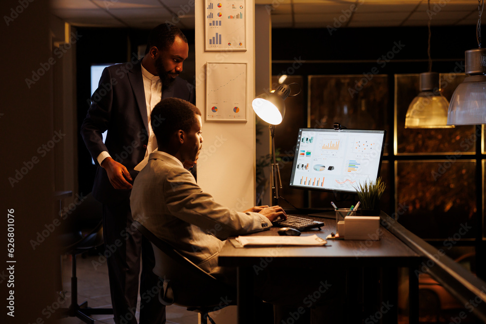 Company workers analyzing financial statistics discussing investment strategy while working overhours in startup office. Businessmen planning brainstorming management ideas. Business concept Company workers analyzing financial statistics discussing investment strategy while working overhours in startup office. Businessmen planning brainstorming management ideas. Business concept