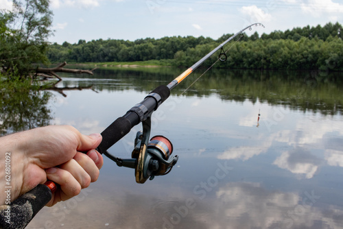 fishing rods in a man's hand on the background of a river with nature 
