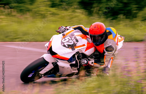 A motorcycle racer is driving fast on a motorcycle track.