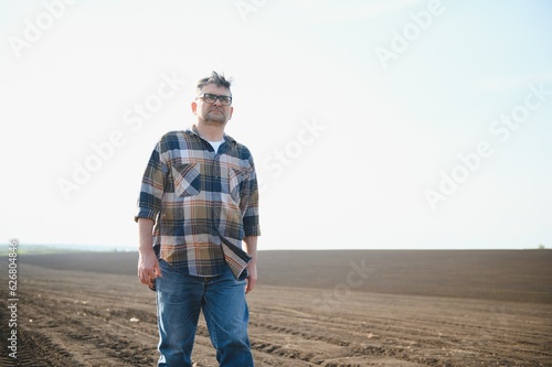A farmer works in a field sown in spring. An agronomist walks the earth, assessing a plowed field in autumn. Agriculture. Smart farming technologies.