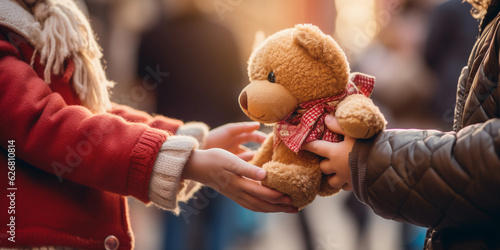 Foto Poignant image of a child's hand receiving a teddy bear at a charity event, shal