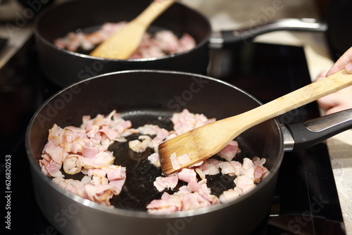 frying bacon in small pieces in a frying pan