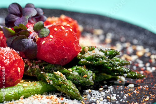 Salad with baked asparagus and tomatoes in a plate on a blue background