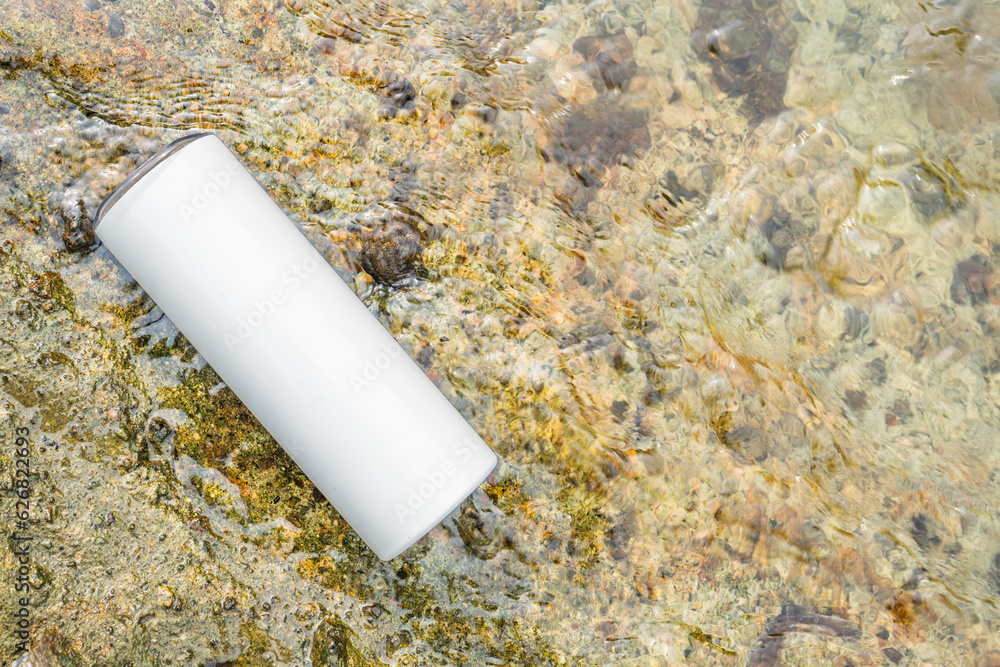 Nature's splendor meets modern style in this captivating mockup image of a white blank long wine tumbler placed alongside a meandering river Nature's splendor meets modern style in this captivating mockup image of a white blank long wine tumbler placed alongside a meandering river