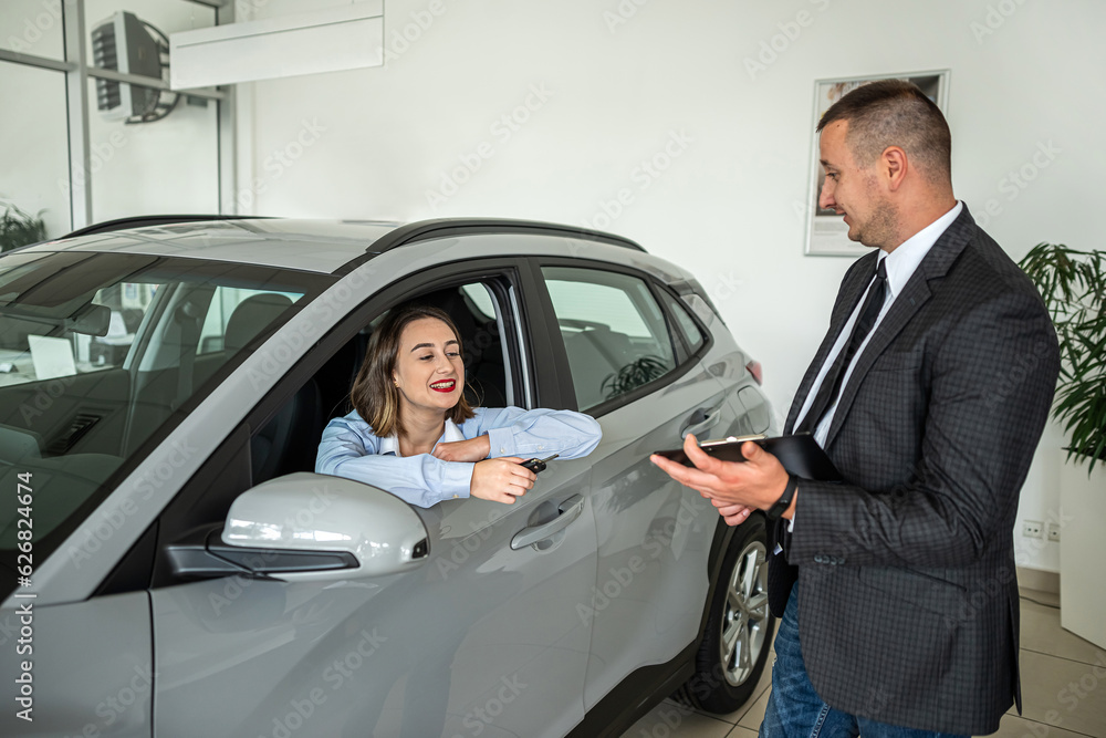 man car seller talking with female buyer about selling a new modern car in luxury dealership center