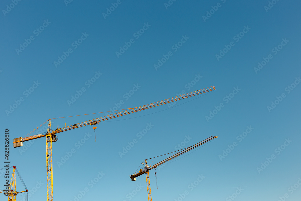 Construction site with three yellow cranes and a blue sky Construction site with three yellow cranes and a blue sky