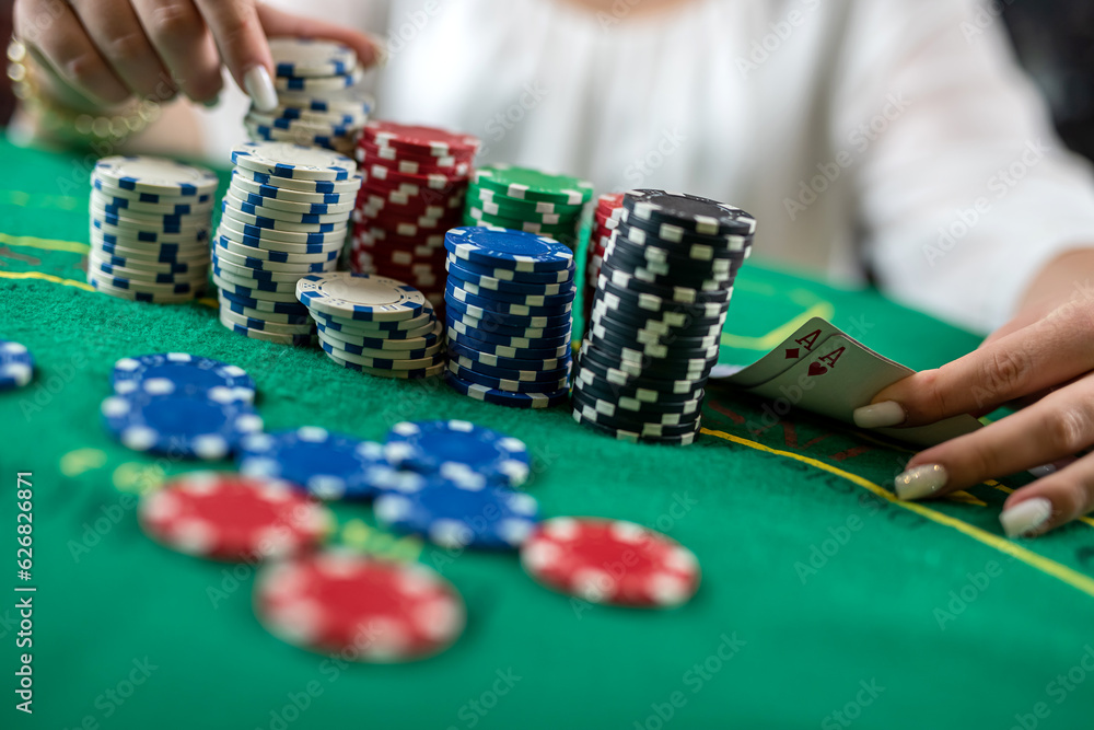 female hands pick up poker chips from a pile at a round poker table. risky bets in poker female hands pick up poker chips from a pile at a round poker table. risky bets in poker