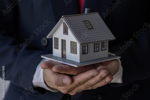 Mortgage concept. Small toy house in business man hand buy or sell real estate Financial agent complete Home sales and home insurance concept, 