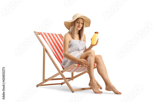 Woman sitting on a deck chair and putting on sun cream