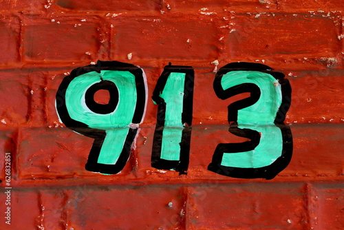 Numéro 913. Numéro de rue peint sur mur de brique rouge.