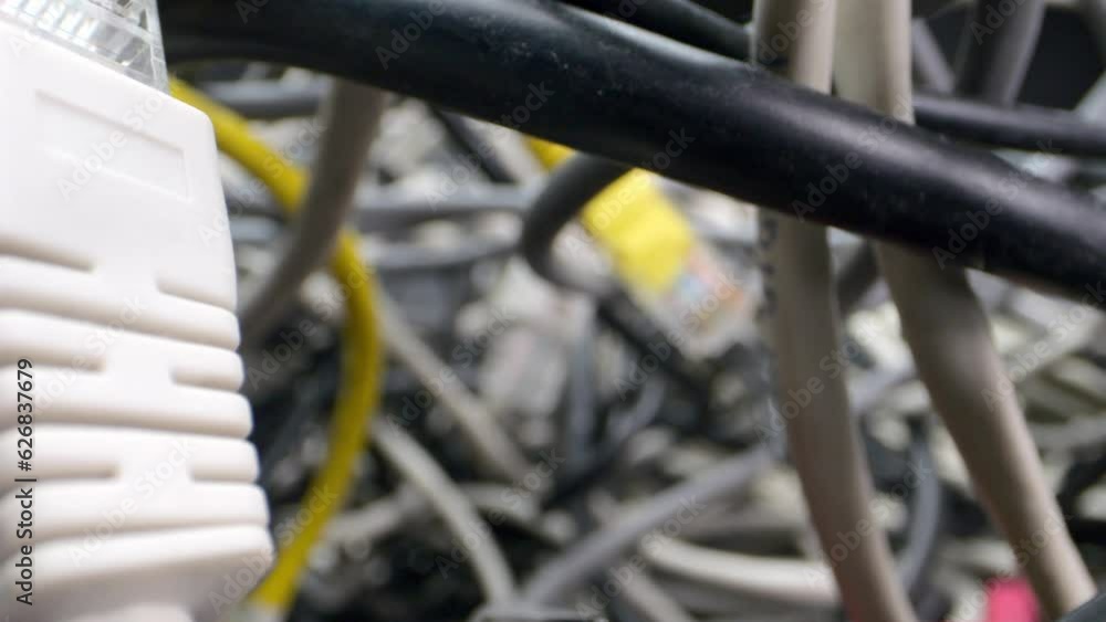 The camera penetrates the tangle of network cables and more. Disordered cables, computer problems galore.