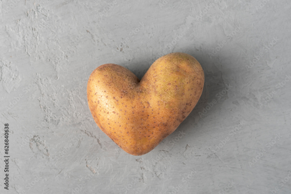 Obraz premium Heart shaped potatoes on a gray concrete background. Top view.