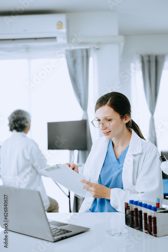 Two scientist or medical technician working, having a medical discuss meeting with an Asian senior female scientist supervisor in the laboratory with online reading, test samples and innovation