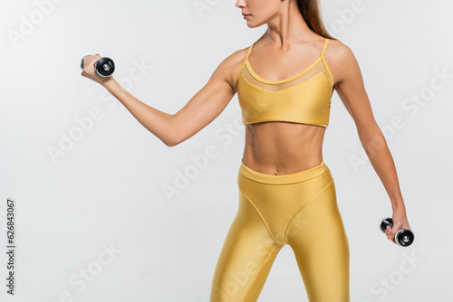 woman in active wear, exercising with dumbbells, white background, motivation, toned body, cropped