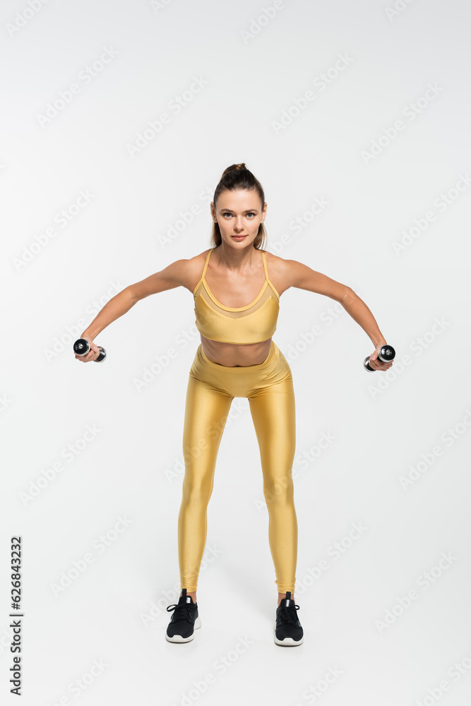 fit sportswoman in fitness clothes training with dumbbells on white background, fitness motivation