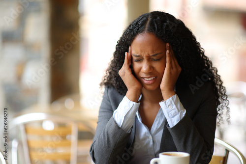 Black businesswoman suffering migraine in a bar