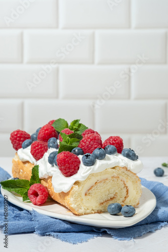 Sponge biscuit cake roll filling whipped cream and berries decorated raspberry  blueberry