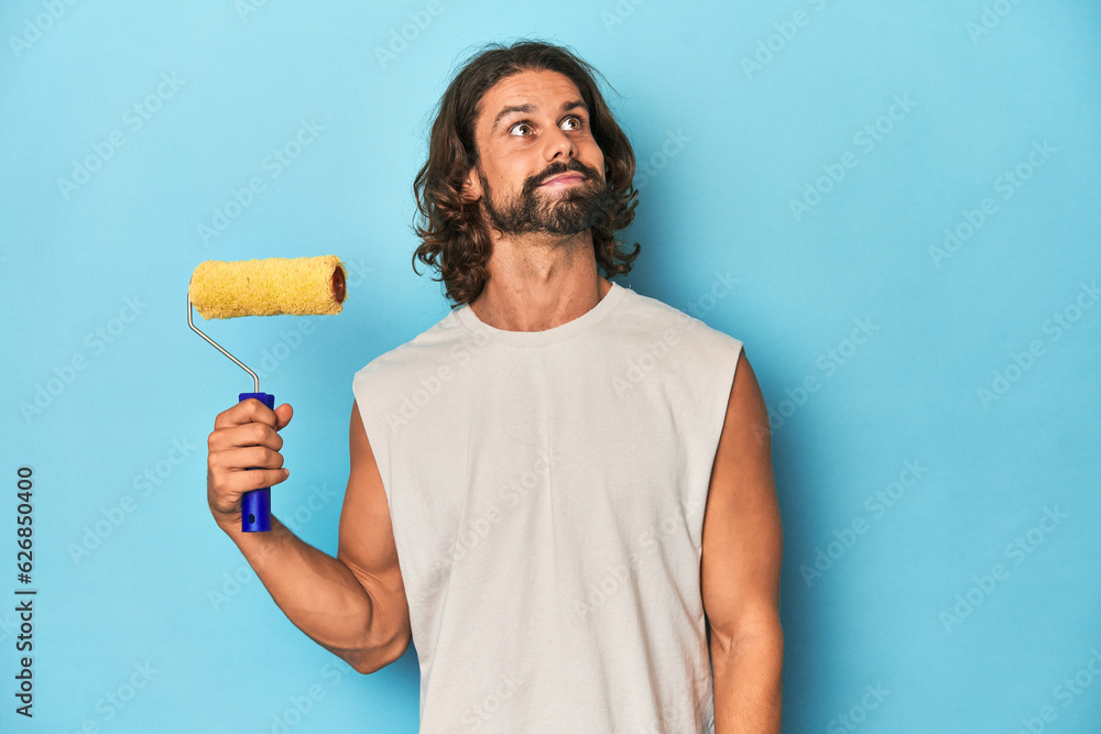 Bearded man painting with a yellow roller dreaming of achieving goals and purposes Bearded man painting with a yellow roller dreaming of achieving goals and purposes